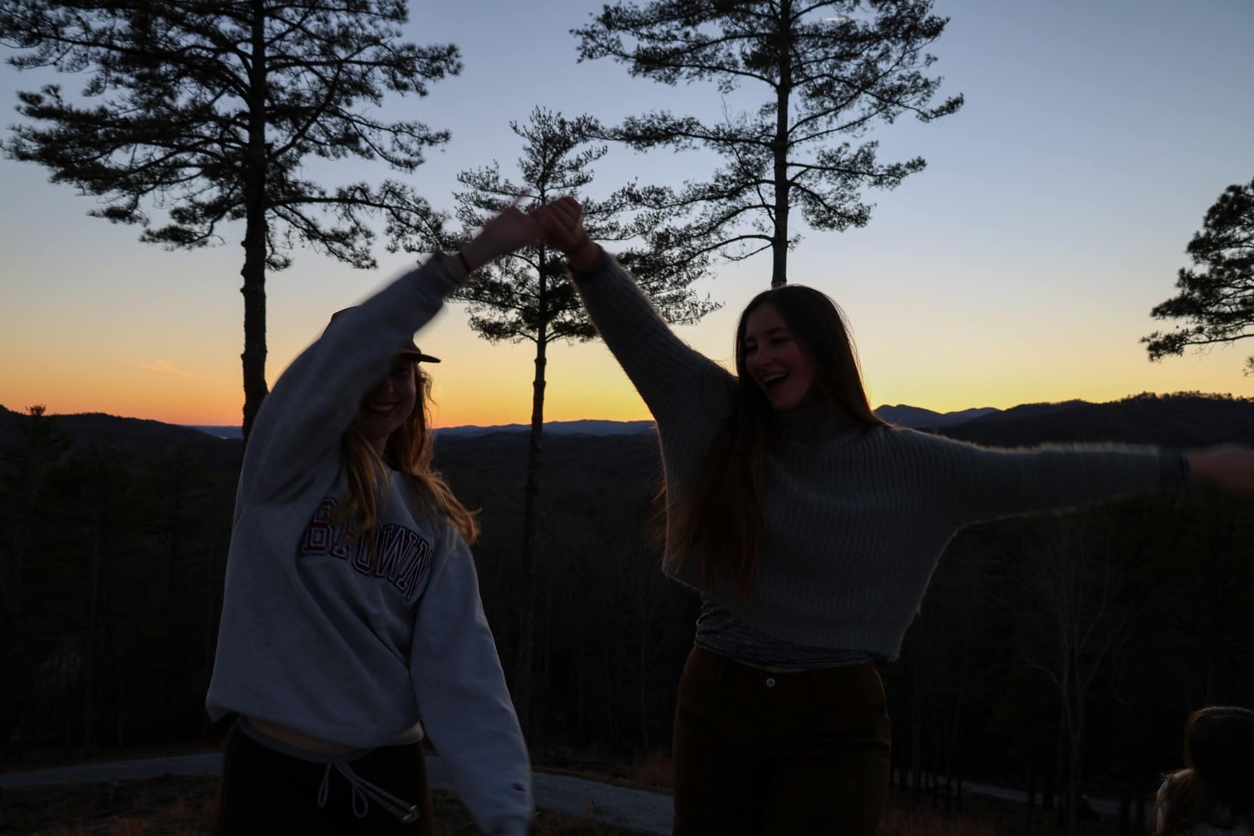 Friends dancing together outside at sunset during Winter Retreat