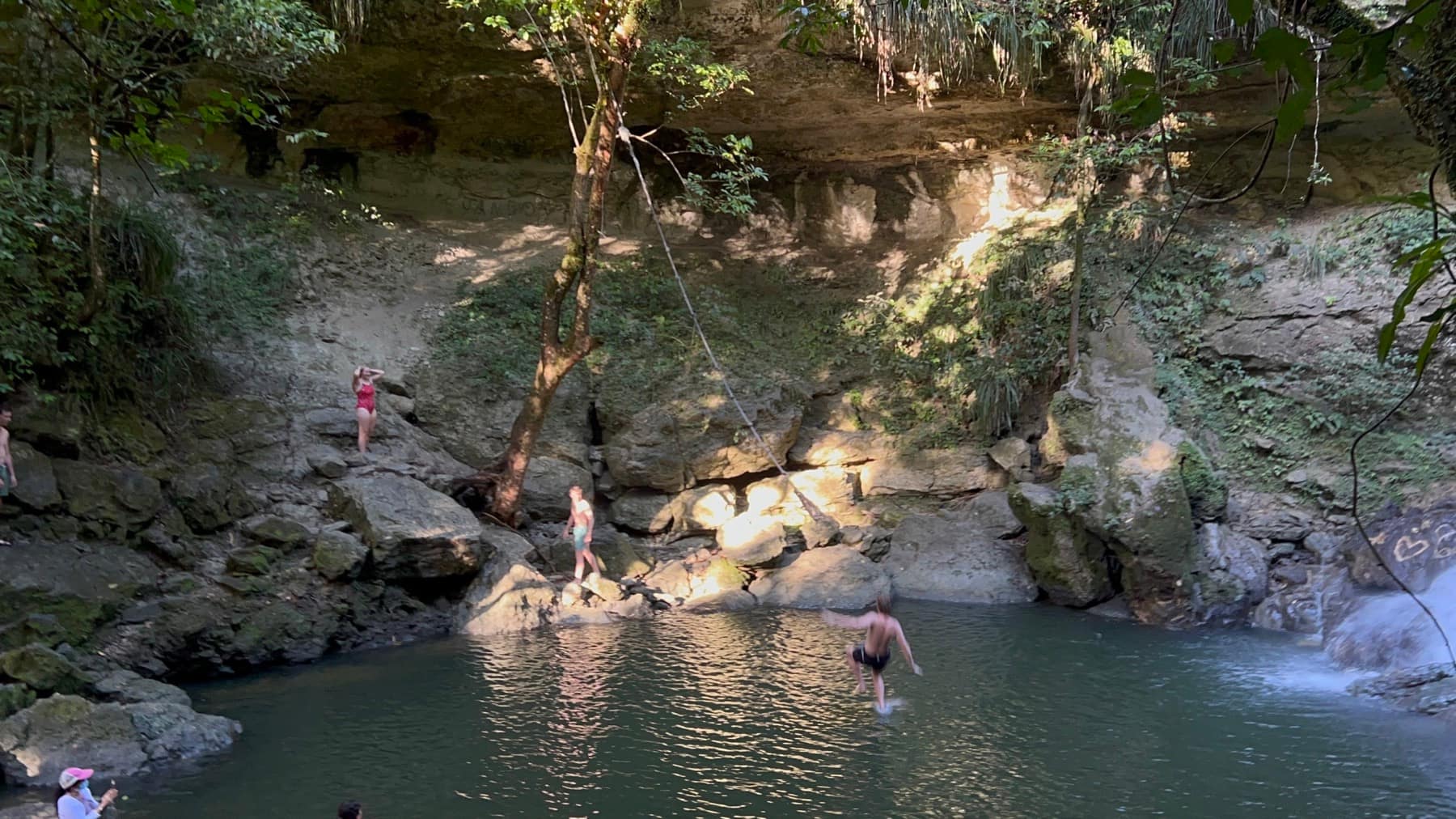 Friends swimming together beneath a Puerto Rico waterfall
