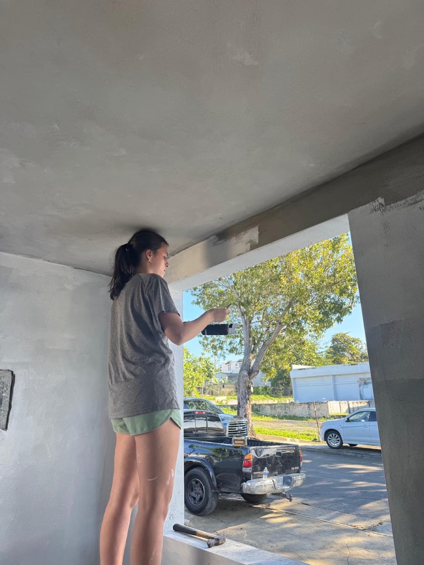 A student painting an exterior wall during the service project